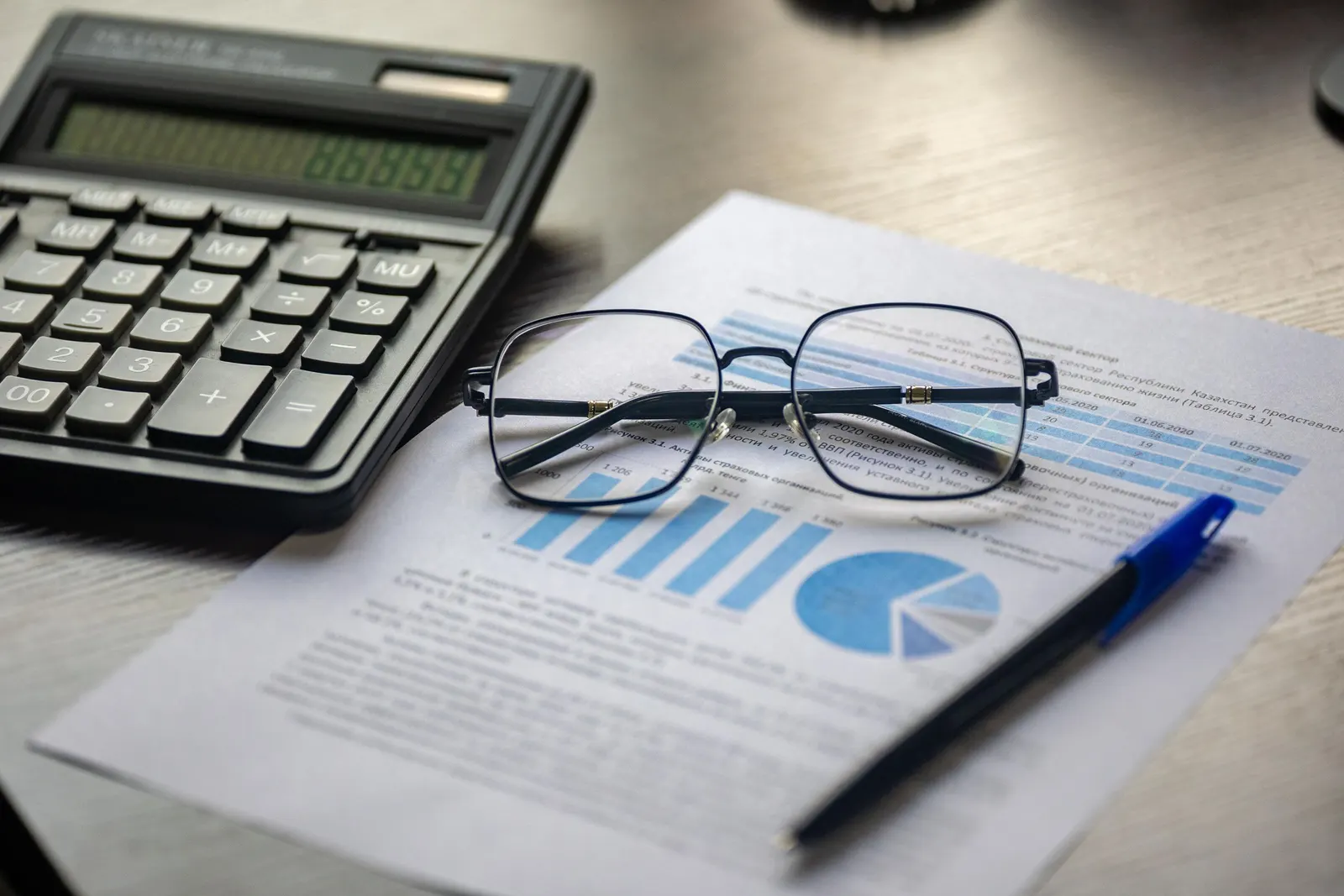 A printed statement with a calculator, reading glasses and a pen