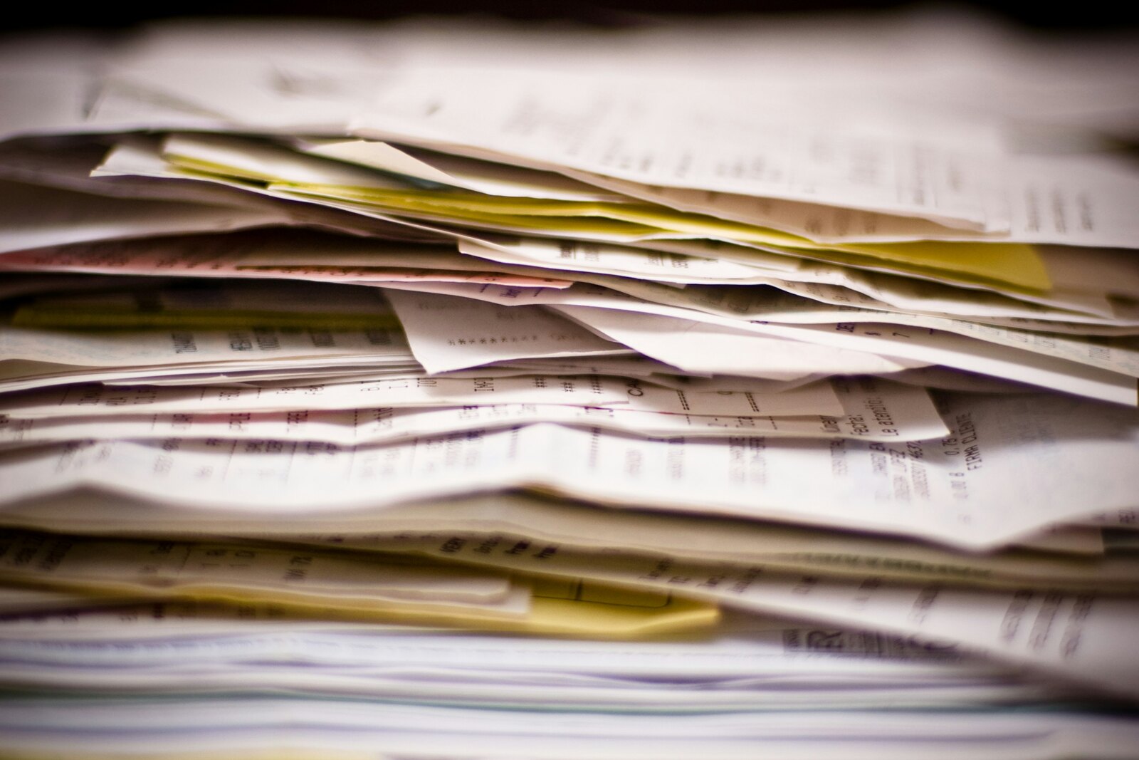 Close-up of a tall, messy stack of receipts, invoices and statements